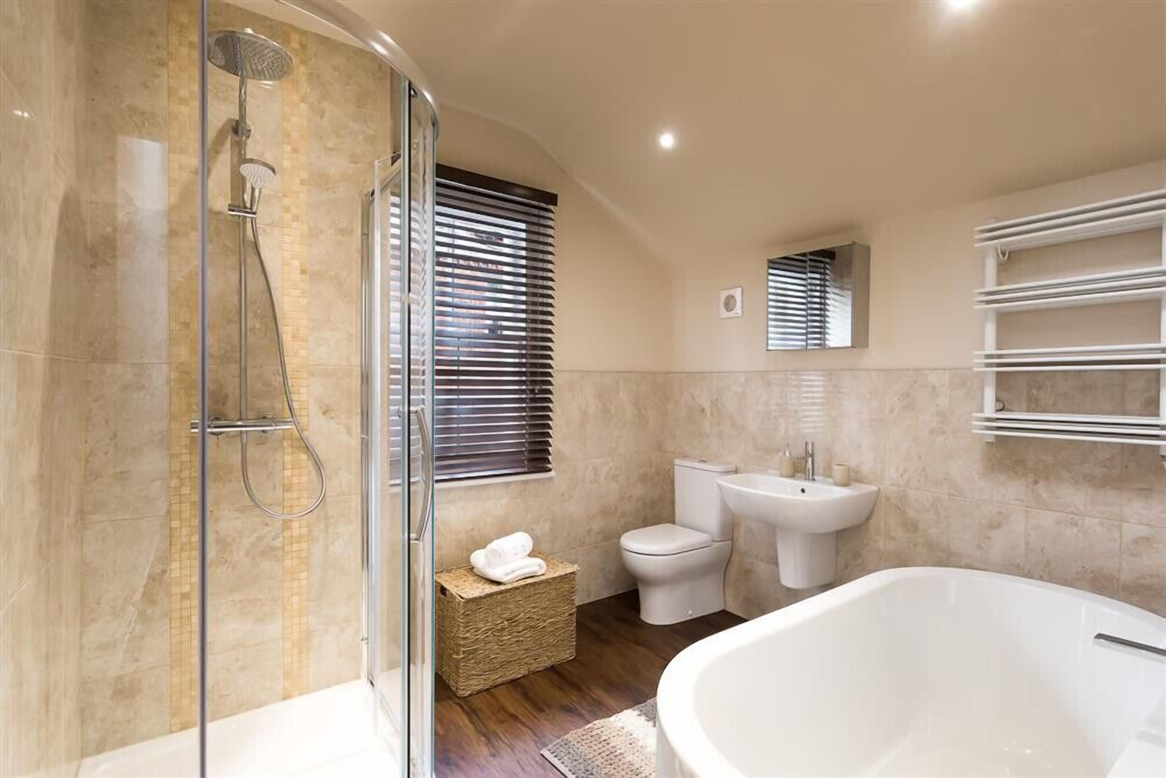 A modern bathroom with a glass-enclosed shower, a freestanding bathtub, a toilet, and a sink.