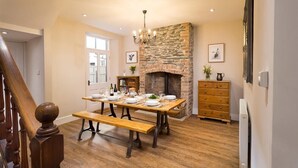 A dining area with a stone fireplace, wooden furniture, and a chandelier. - Thirty Blencathra Street (Keswick)