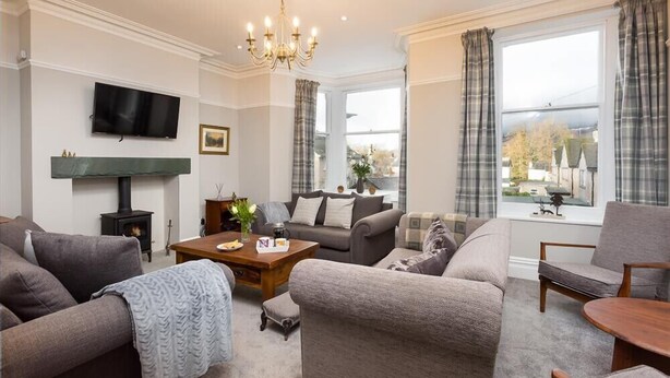 A living room with a fireplace, a television, and a large window with curtains. - Thirty Blencathra Street (Keswick)