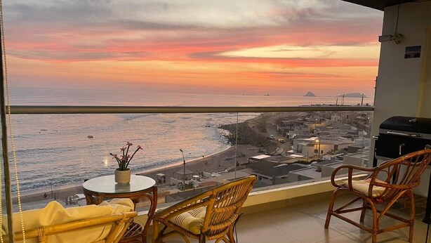 A balcony with wicker chairs and a small table, overlooking a beach and cityscape during sunset. - 𝐃𝐄𝐏𝐀 𝐂𝐎𝐍 𝐄𝐒𝐏𝐄𝐂𝐓𝐀𝐂𝐔𝐋𝐀𝐑 𝐕𝐈𝐒𝐓𝐀 𝐀𝐋 𝐌𝐀𝐑🌅 Punta Hermosa  (Punta Hermosa)