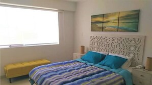 A bedroom with a bed, a bench, a nightstand, a wall-mounted artwork, and a window. - 𝐃𝐄𝐏𝐀 𝐂𝐎𝐍 𝐄𝐒𝐏𝐄𝐂𝐓𝐀𝐂𝐔𝐋𝐀𝐑 𝐕𝐈𝐒𝐓𝐀 𝐀𝐋 𝐌𝐀𝐑🌅 Punta Hermosa  (Punta Hermosa)