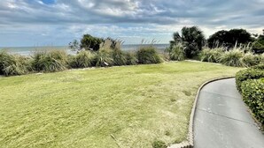 A grassy area with a curved pathway leading to a beach.