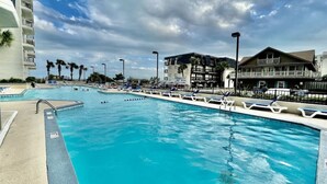 A swimming pool with lounge chairs and a building with balconies in the background.