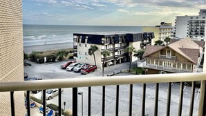 A beachfront hotel with multiple floors, a parking lot, and a view of the ocean.