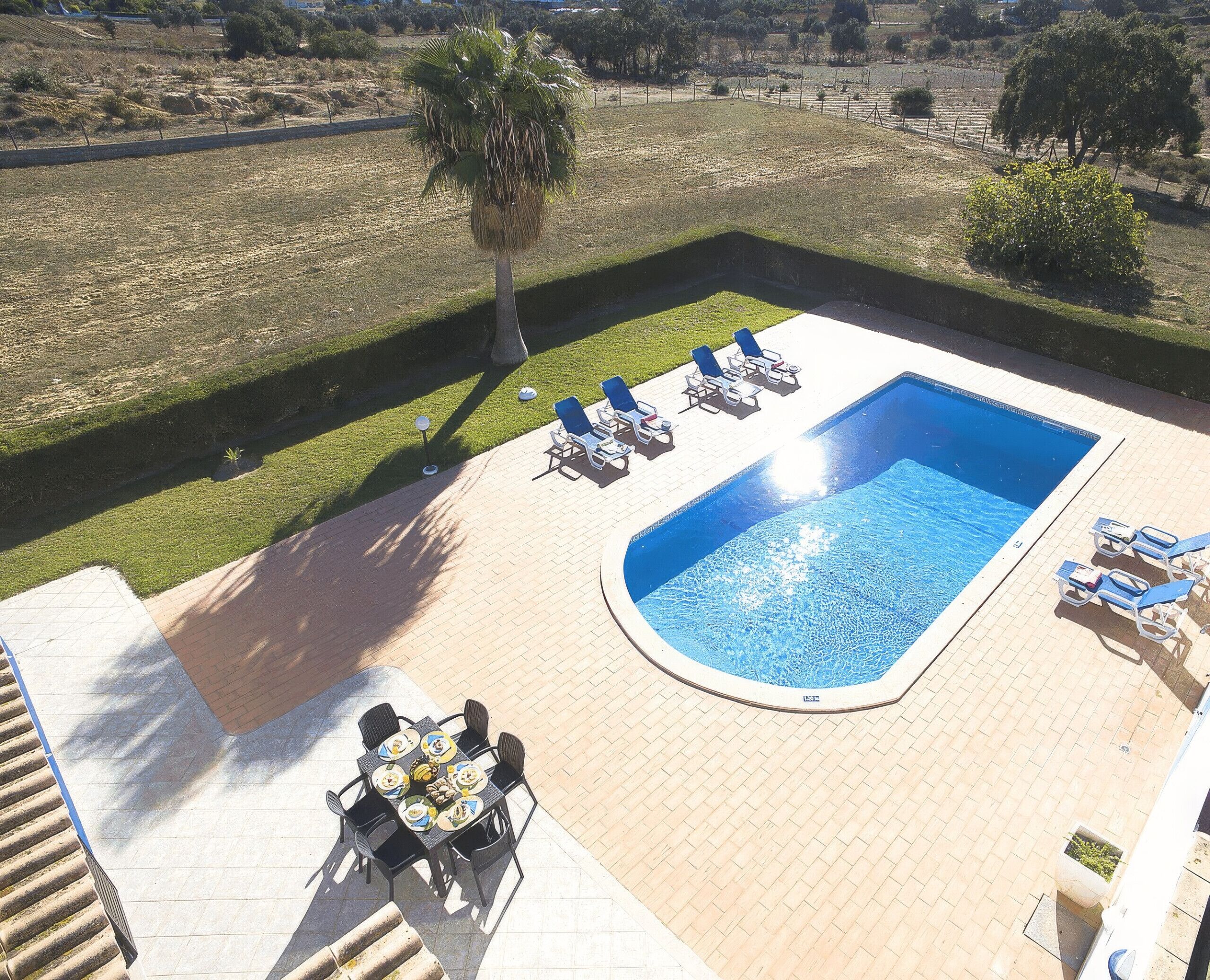 A swimming pool with lounge chairs and a dining table with chairs.