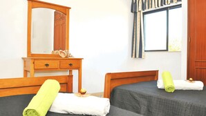 A hotel room with a wooden dresser, a mirror, two beds with towels, a window with curtains, and a wooden door. - Rustic retreat w/ private pool, Guia (Albufeira)