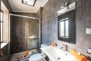 Ein modernes Badezimmer mit einer Duschkabine, einem weißen Waschbecken und einem großen Spiegel.