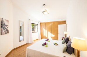 Una habitación de hotel con cama, mesita de noche, lámpara, espejo y ventana con cortinas.