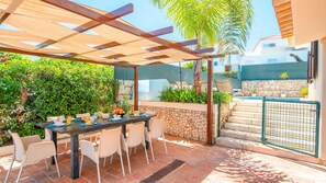 An outdoor patio with a table and chairs, a barbecue grill, and a stone wall. - Spacious villa with heatable pool in Albufeira (Albufeira)