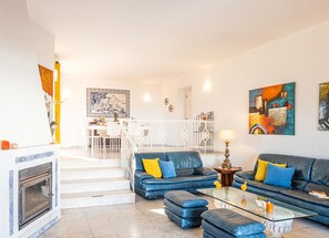 A living room with a blue sofa, a glass coffee table, and a fireplace.