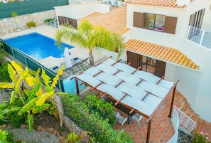 Um imóvel residencial com piscina, área de estar externa e varanda coberta.