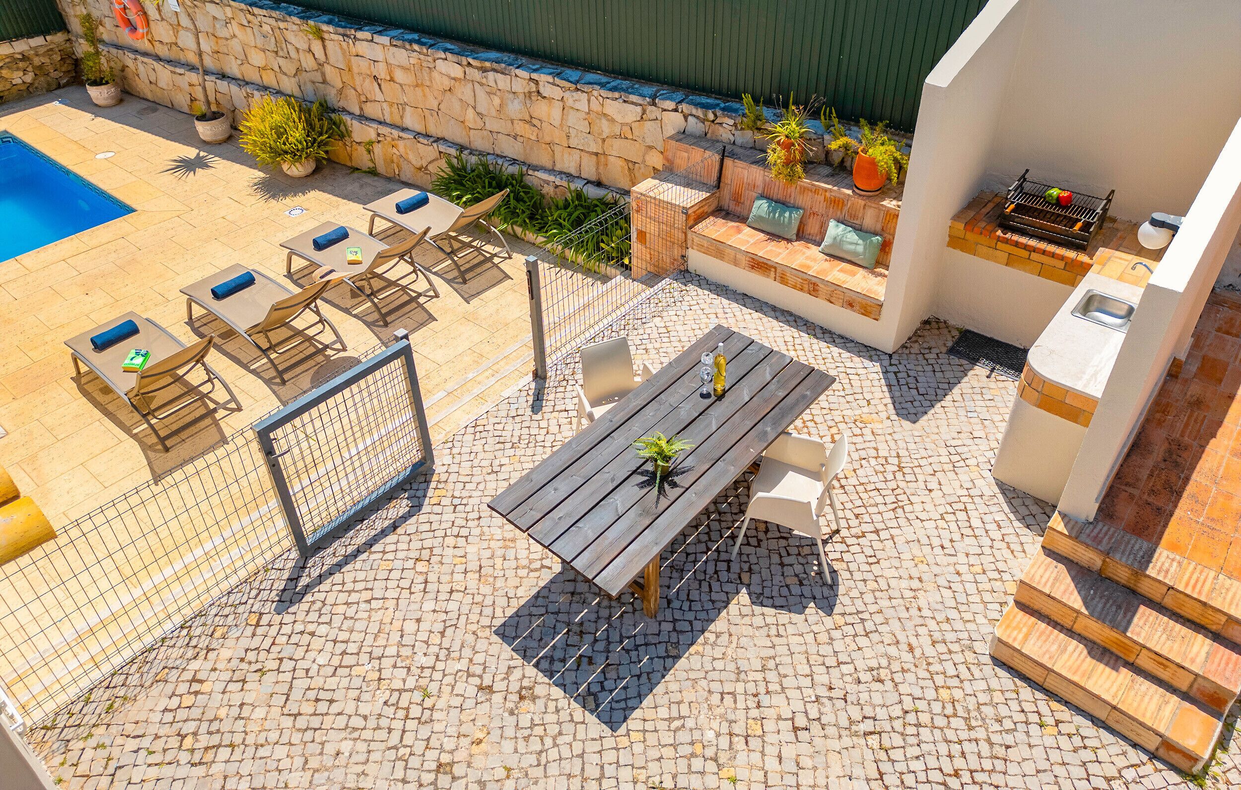 Eine Terrassenanlage im Freien mit Pool, Sitzgelegenheiten und Grillbereich.