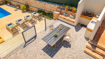 Eine Terrassenanlage im Freien mit Pool, Sitzgelegenheiten und Grillbereich.