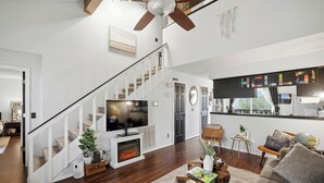 Ein modernes Wohnzimmer mit Kamin, einer Treppe und einer Küchenzeile.