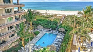 A hotel with a pool surrounded by palm trees and a beach view.
