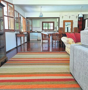 Uma sala de estar espaçosa com um tapete listrado, um sofá e uma área de jantar com cadeiras e mesa de madeira.