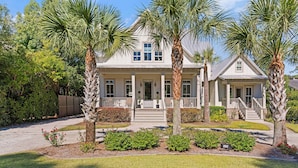 A two-story house with a front porch, palm trees, and a well-maintained garden. - Stollaway Retreat - 5 Bedrooms with Pool (St Simons Island)