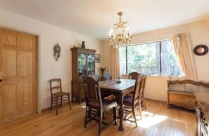 Classic dining room with a traditional table and six chairs, a chandelier, and a wooden cabinet with glass doors.