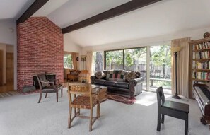 Cozy living room with a brick fireplace, comfortable sofa, and piano.