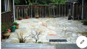 Une terrasse en pierre avec des plantes en pot et une clôture en bois.