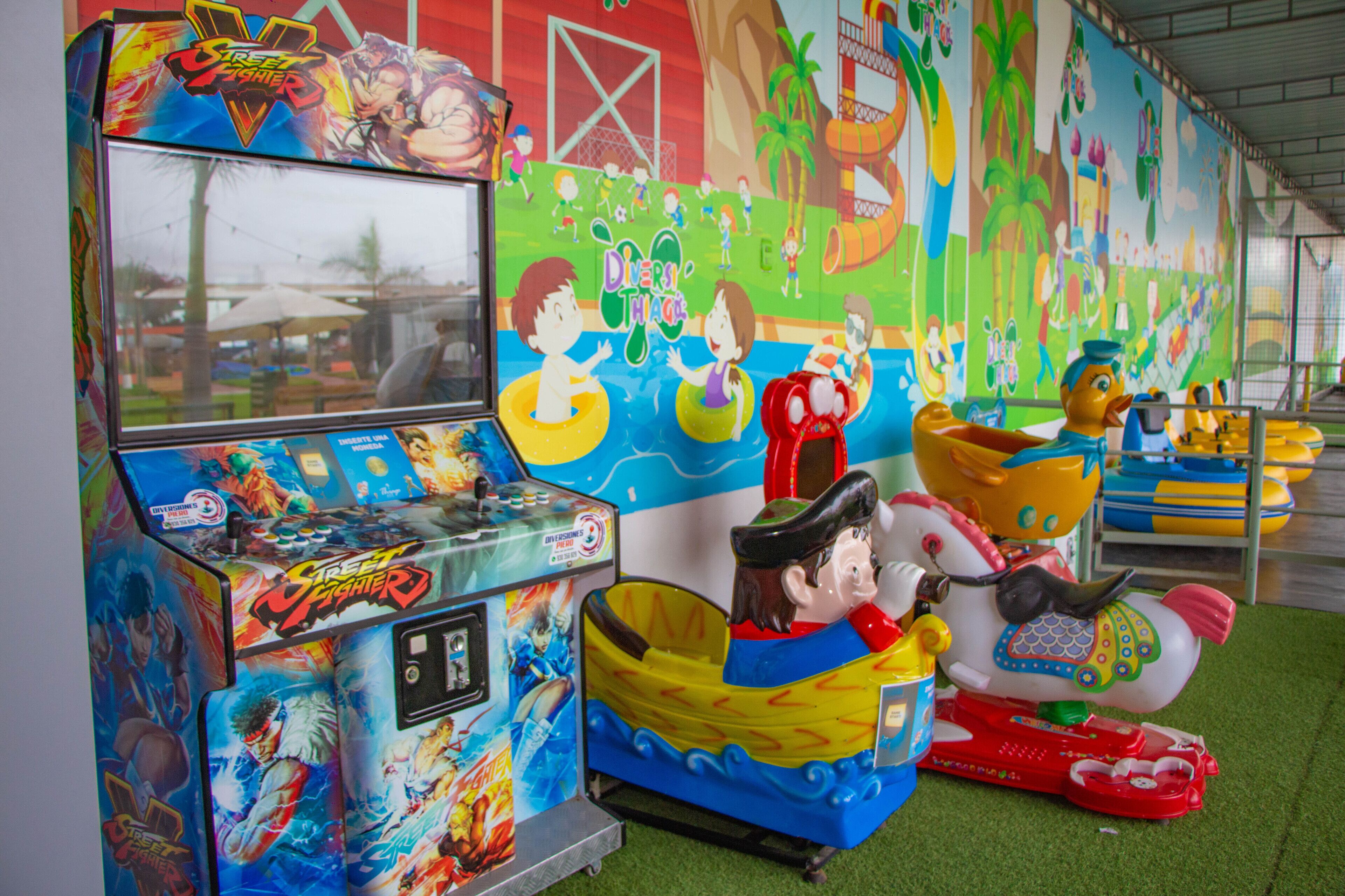 Un salón de juegos colorido con varios juegos y un mural que muestra niños jugando.