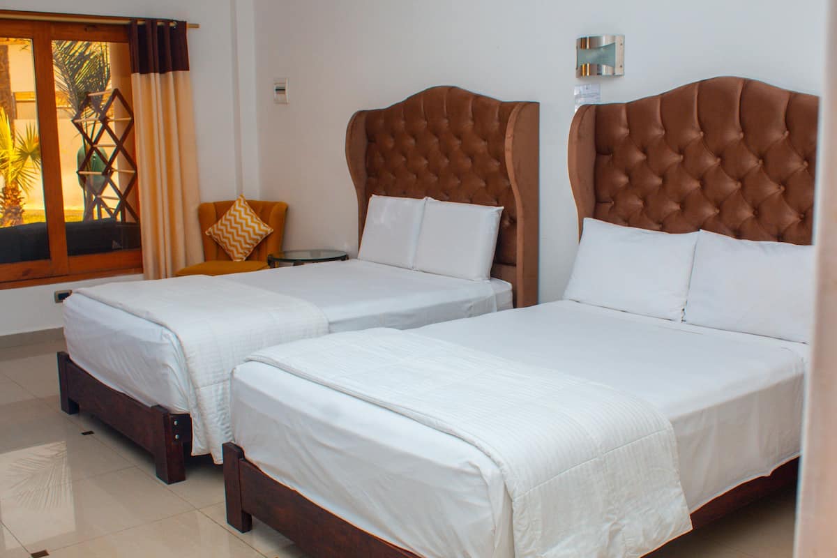 Two twin beds with wooden headboards, white linens, and a small table with a chair.