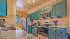 A kitchen with wooden cabinets, granite countertops, stainless steel appliances, and a window providing natural light.