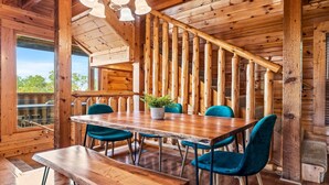 A wooden interior with a dining table, four chairs, and a staircase.