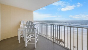 A balcony with white Adirondack chairs overlooking a beach. - Gulf Shores Condo Clearwater 8C | Sleeps 6 (Gulf Shores)
