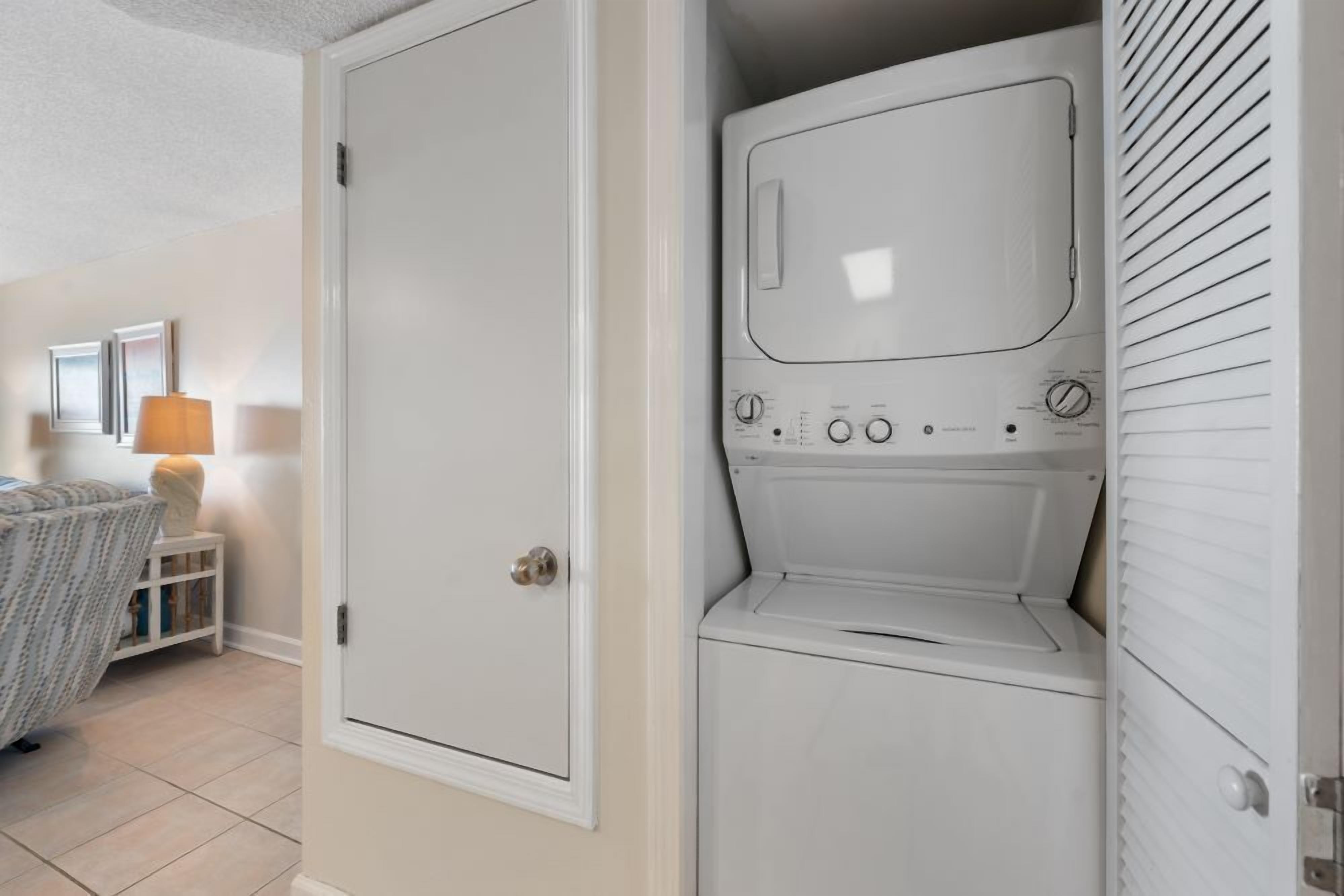 Une buanderie équipée d’un lave-linge et d’un sèche-linge, avec une porte et une petite table sur laquelle se trouve une lampe.