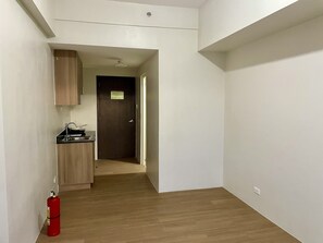 A narrow hallway with a wooden cabinet and a small kitchen area. - The Loop Condotel (Cagayan de Oro)