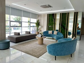 A modern lobby with a sectional sofa, a blue armchair, and a coffee table with a sign about social distancing. - The Loop Condotel (Cagayan de Oro)