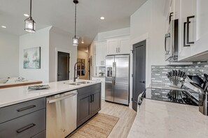 A modern kitchen with stainless steel appliances, white cabinetry, and a marble countertop. - *Desert Escape- With a Private Hottub & Firepit* (Washington)