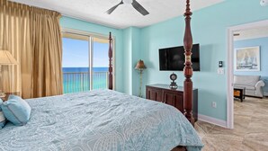 Ein Schlafzimmer mit Bett, Deckenventilator, Fernseher und Meerblick.