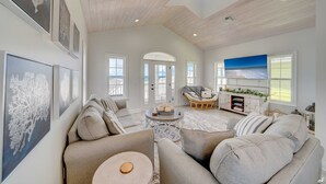A spacious living room with a high ceiling, a large TV, and a cozy seating area. - Summer Towne cottage w/ pool and beach access (Panama City Beach)