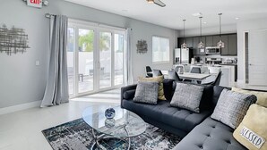 A modern living room with a sofa, a glass coffee table, and a view to the outside. - Luxury Resort Style Condo Near Disney-103 (Kissimmee)