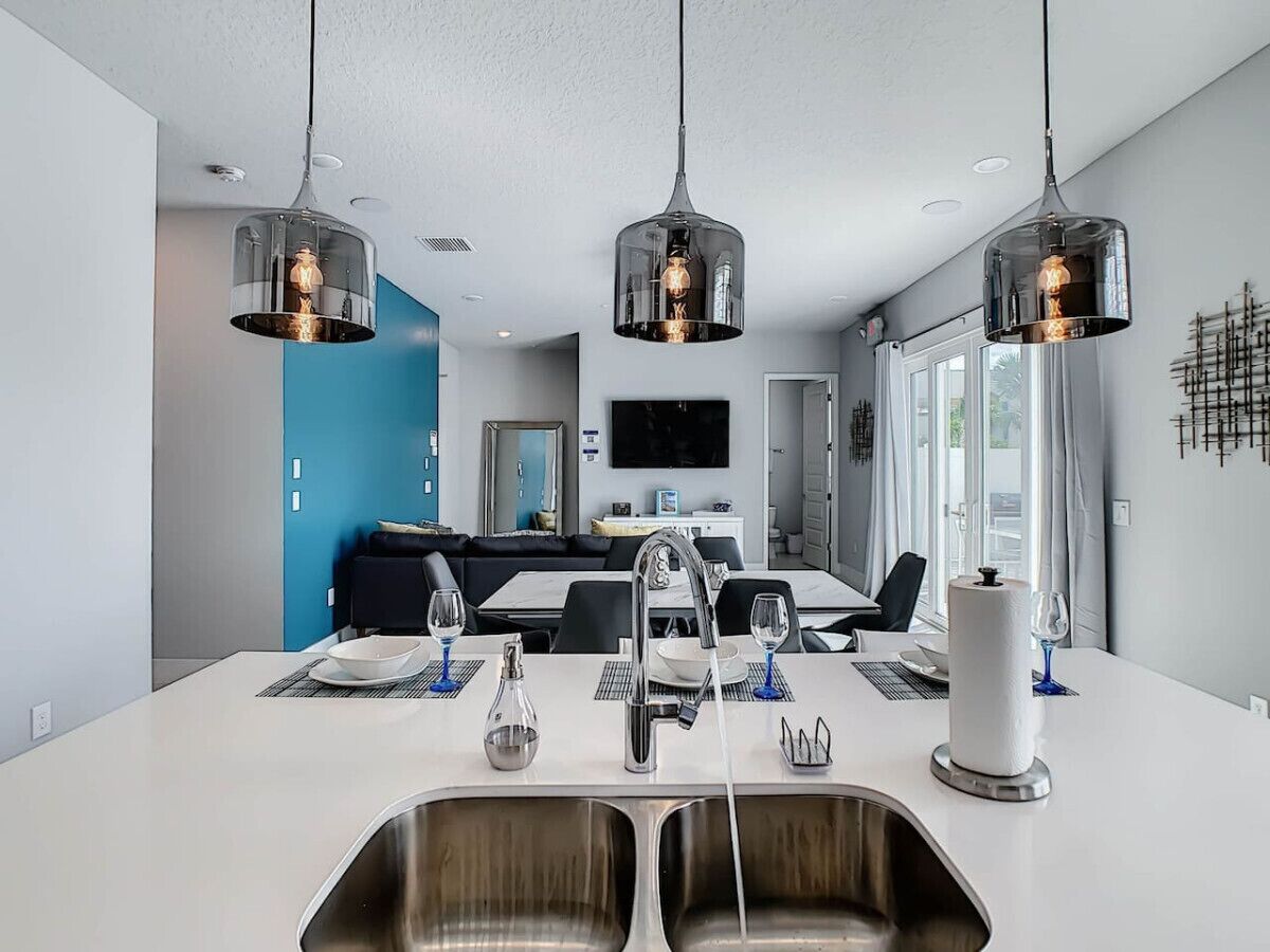 A modern kitchen with a central island, stainless steel sinks, and pendant lighting.
