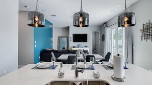 A modern kitchen with a central island, stainless steel sinks, and pendant lighting. - Luxury Resort Style Condo Near Disney-103 (Kissimmee)