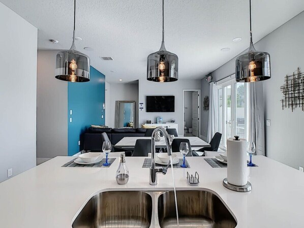 A modern kitchen with a central island, stainless steel sinks, and pendant lighting.