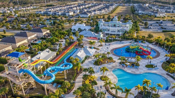 An aerial view of a resort with a water park, including a large pool and a water slide.