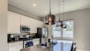 A modern kitchen with white cabinets, stainless steel appliances, and a large island with seating.