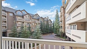 A multi-story residential building with balconies, surrounded by trees and a clear sky. - Saint James Place 116 (Beaver Creek)