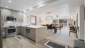 A modern kitchen with built-in appliances, a dining area with a large table and chairs, and a view of the outdoors. - Saint James Place 116 (Beaver Creek)