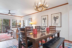 A dining area with a wooden table, chairs, a bench, and a chandelier.