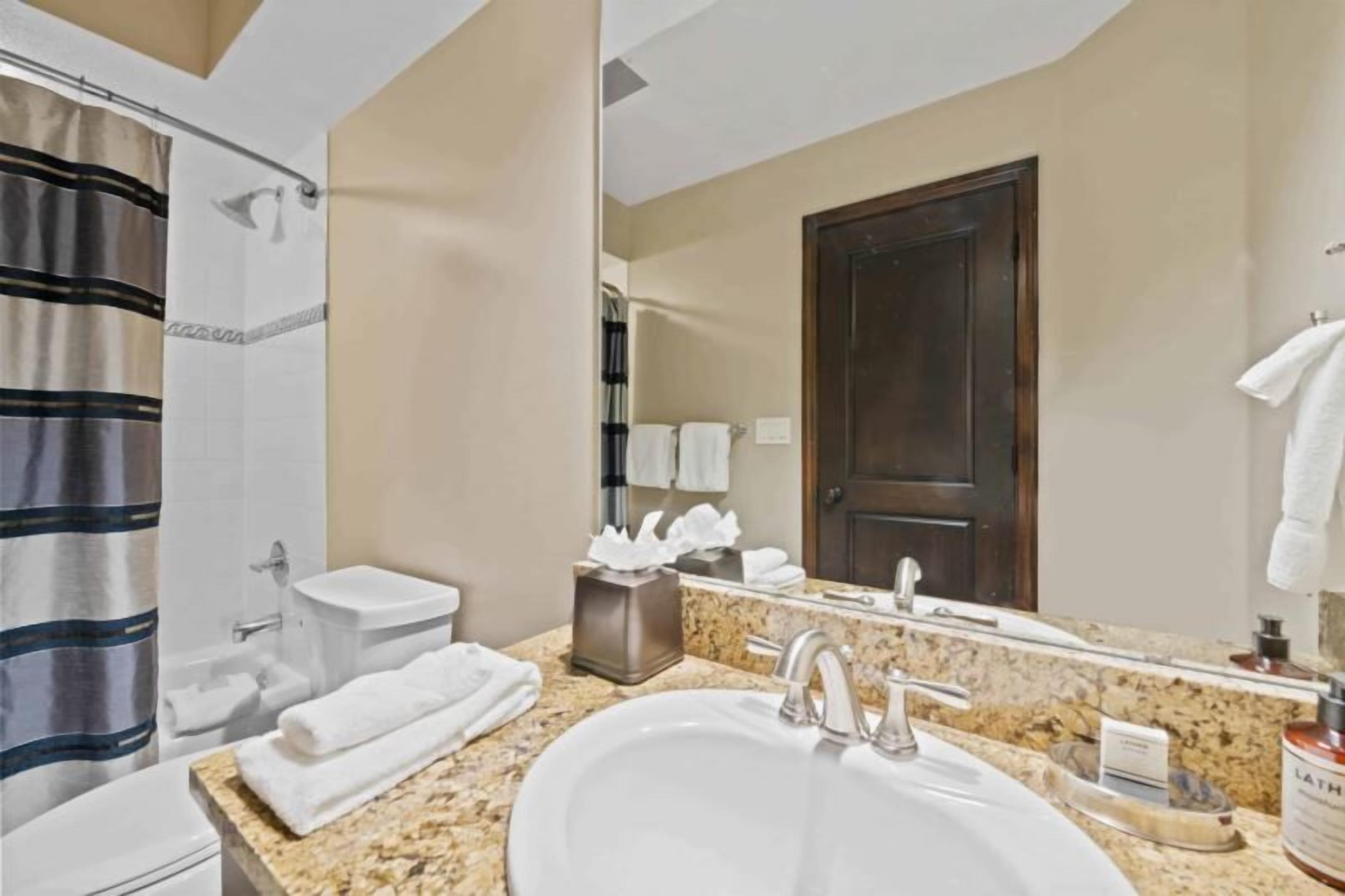 A bathroom with a sink, mirror, towel rack, and shower curtain.