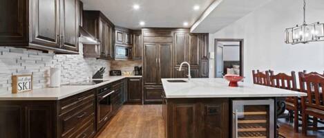 A modern kitchen with dark wood cabinets, a white countertop, and a built-in wine cooler.