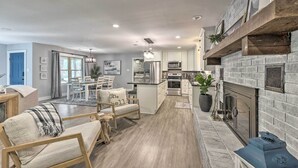 A modern kitchen with a stone fireplace, wooden shelves, and a dining area with a view to the outdoors. - Updated Royal Retreat on 5 Acres: 'Hidden Creek' (Royal)
