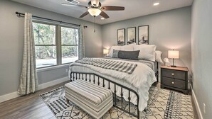 A bedroom with a bed, a nightstand, a bench, a ceiling fan, and a window with curtains. - Updated Royal Retreat on 5 Acres: 'Hidden Creek' (Royal)
