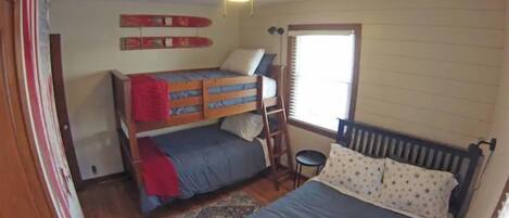 A bedroom with a bunk bed, a single bed, a ceiling fan, and a window with blinds.