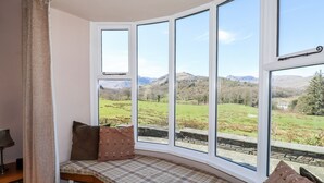 A corner seating area with a view of a green landscape and mountains. - Spindle Coppice (Ambleside)